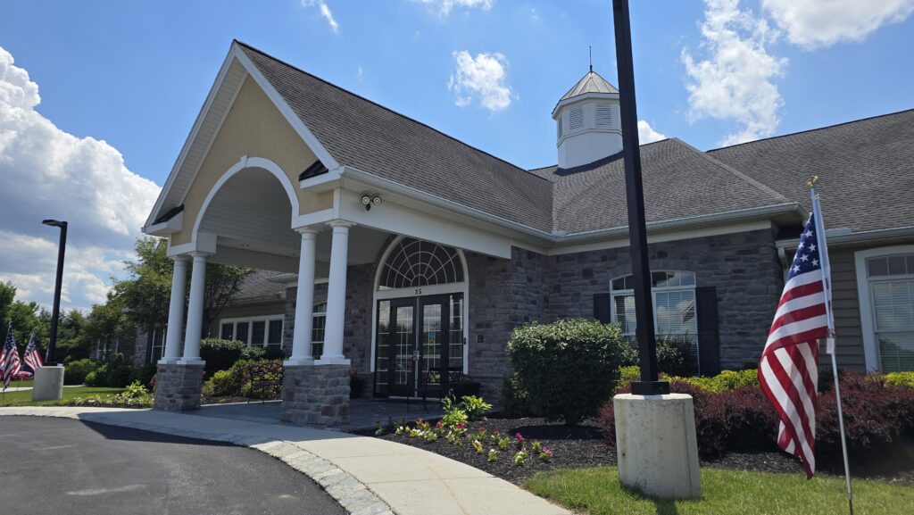 Front right angle somewhat close up image of the common area clubhouse at Traditions of America at Silver Spring in Mechanicsburg, PA - image is for the community amenities section of the home listing home for sale in the neighborhood at 145 James Madison Dr, Unit 237, Mechancisburg, PA 17050